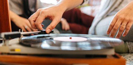 "Is Vinyl Better Than Digital Music?" Low-angle view of female friends listening to old records and smiling. Vinyl