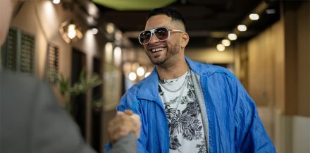 "How to Get a Music Booking Agent" - Mid-shot front view of cheerful male artist shaking hands with business manager after reaching agreement over new contract deal